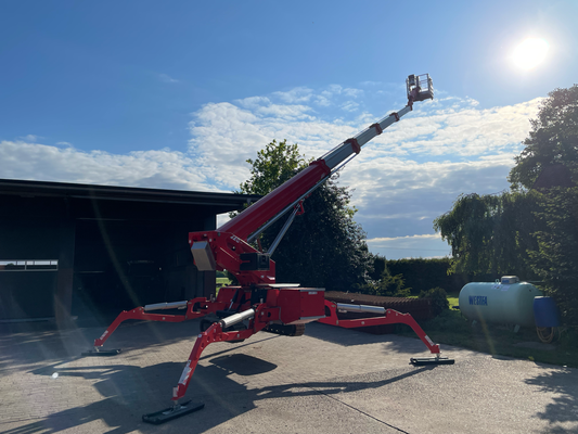 Raupen-Arbeitsbühne auf Hof mit ausgefahrenem Ausleger